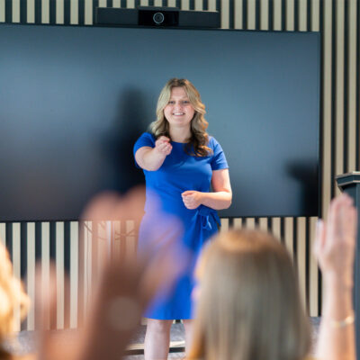 Wellbeing Consultancy trainer leads a session in front of a large display and podium.