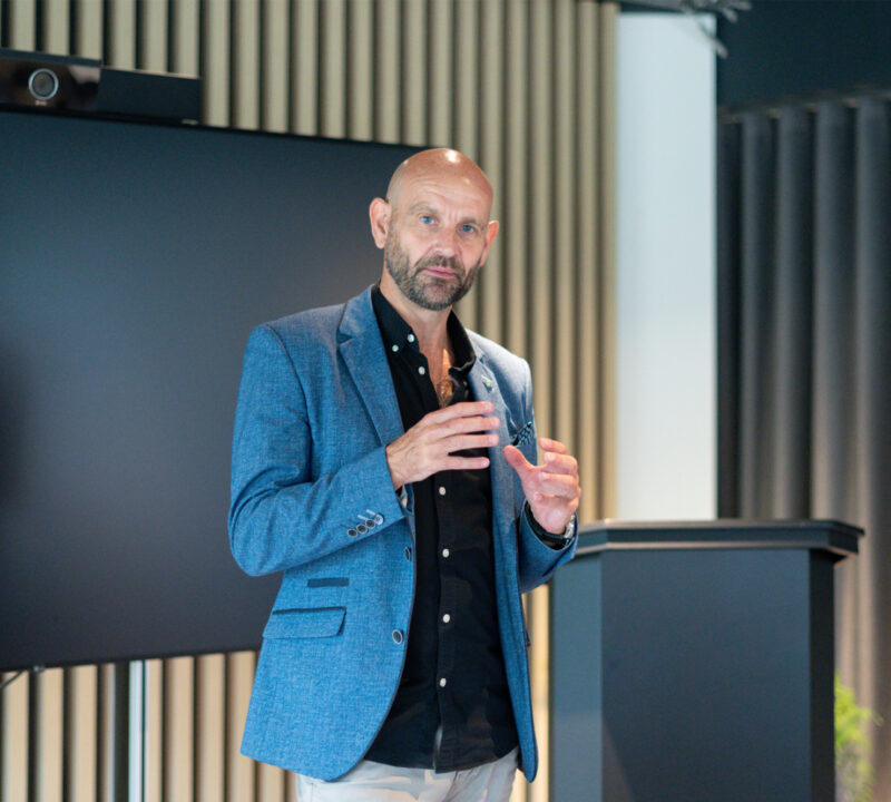 Wellbeing Expert leads a Mental Health talk in front of a screen and podium.