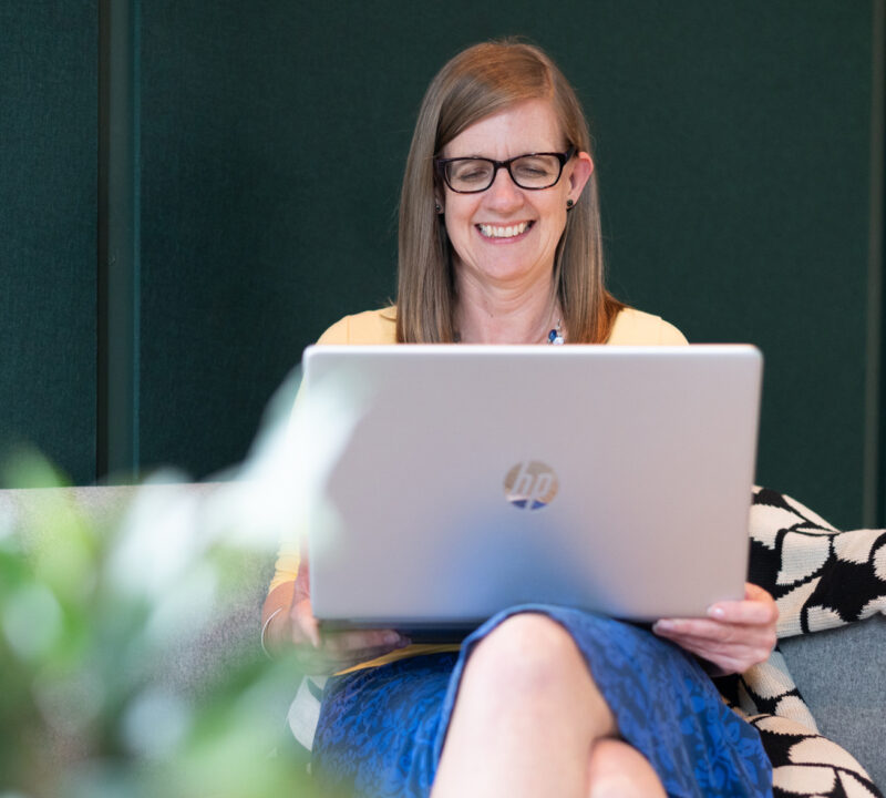 Participant sat on a sofa using a laptop to access online wellbeing courses.